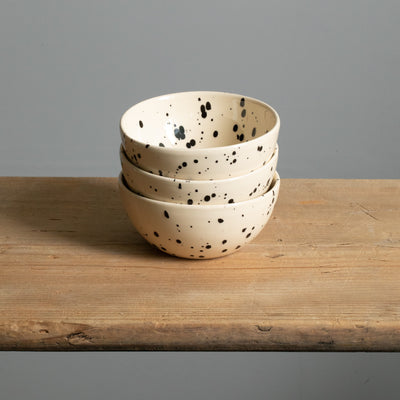 Three large snack bowls stacked in the color cream with black dots