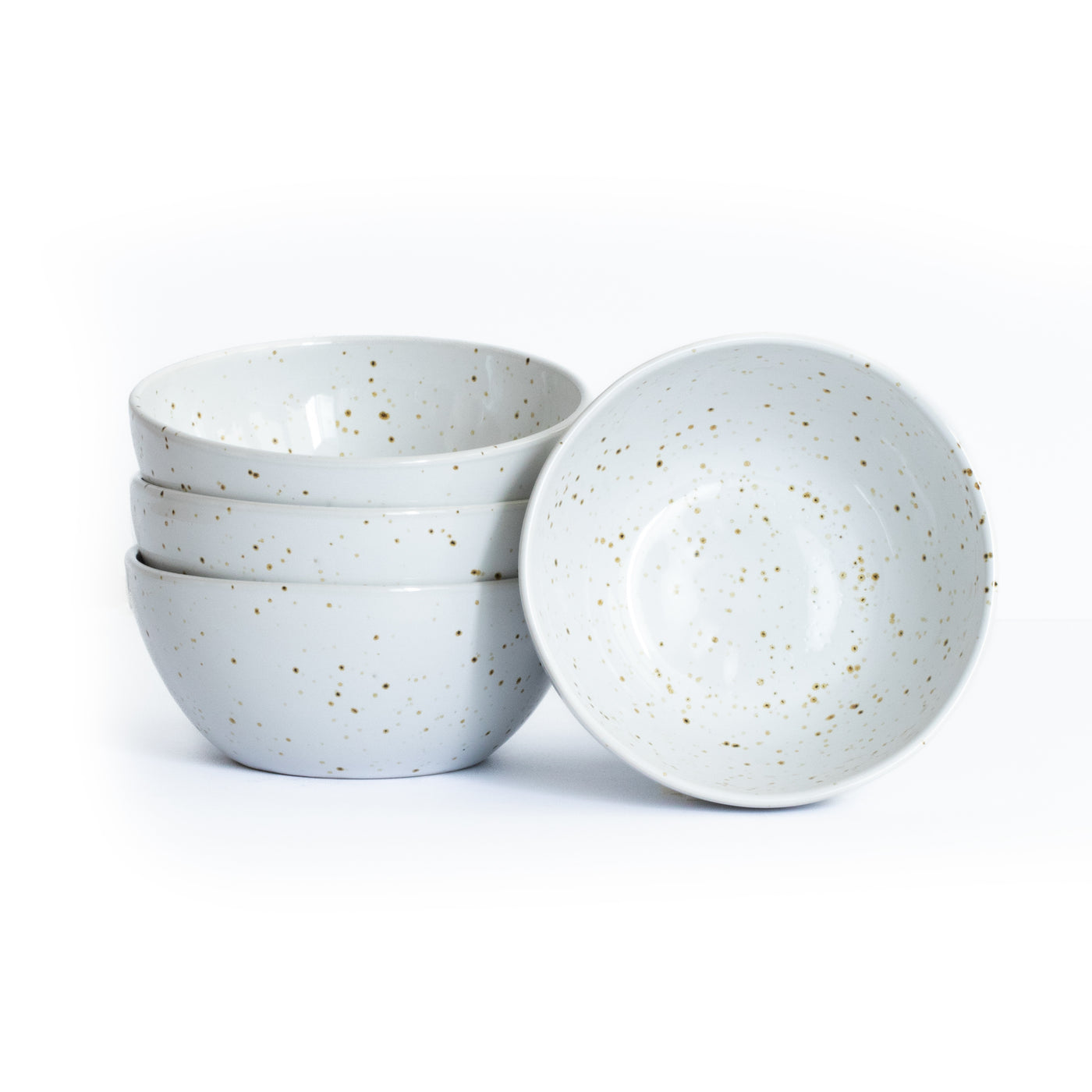Three stacked and one upright large snack bowl in white color with golden brown sprinkles isolated against a white background