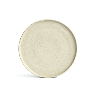 A large plate in matt speckled beige set up with angled edge against a white background, cropped
