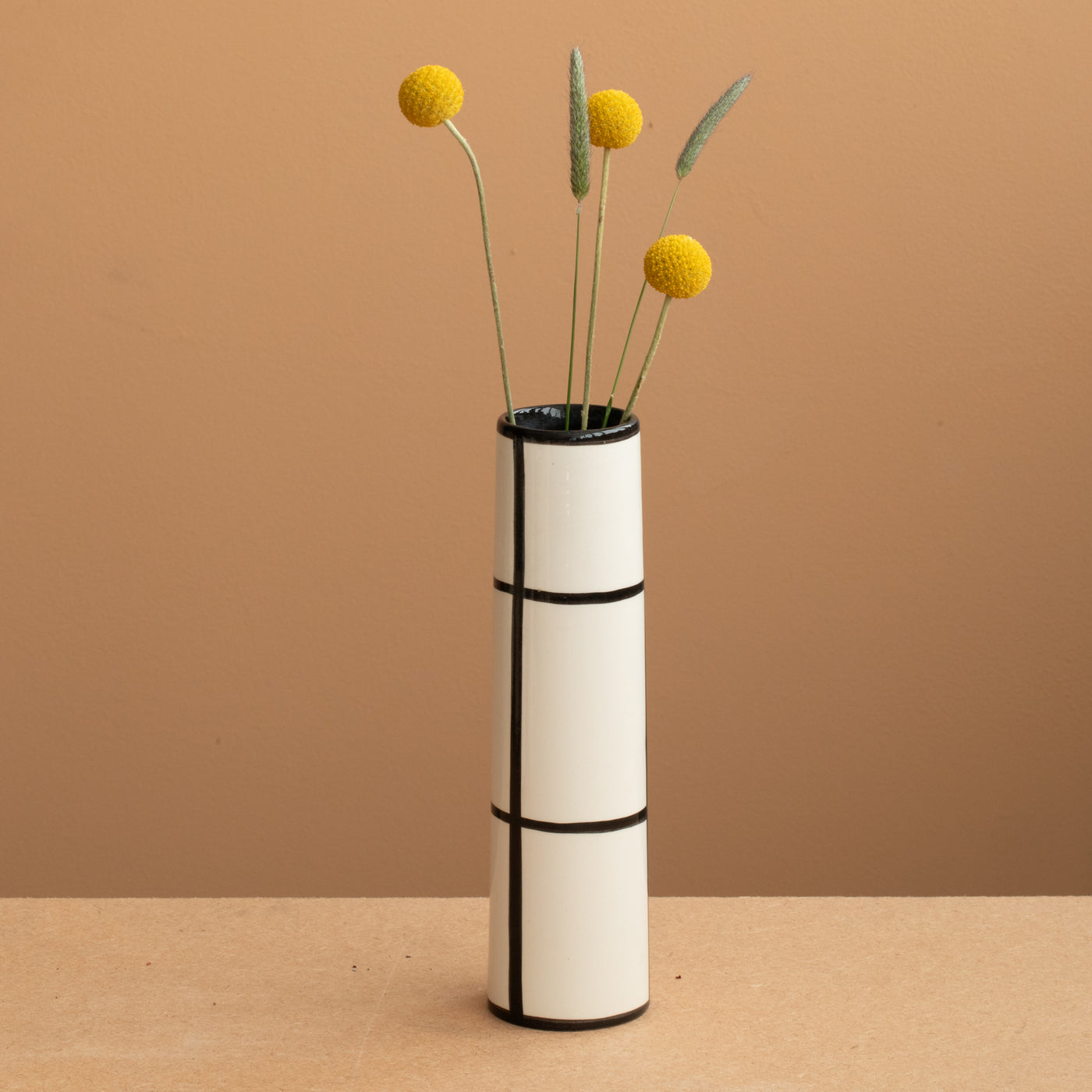 Thin vase in white color black checkered and yellow and green flowers