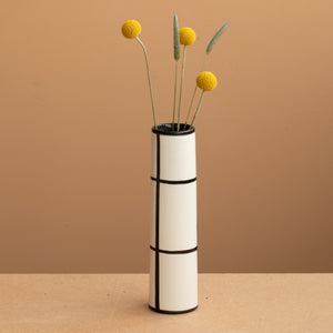Thin vase in white color black checkered and yellow and green flowers
