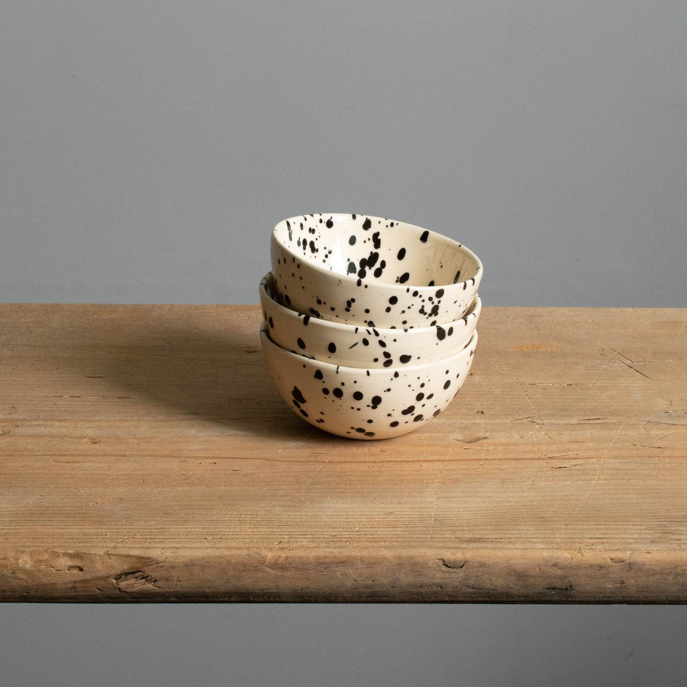 Three small snack bowls in cream with black splashes of color.stacked