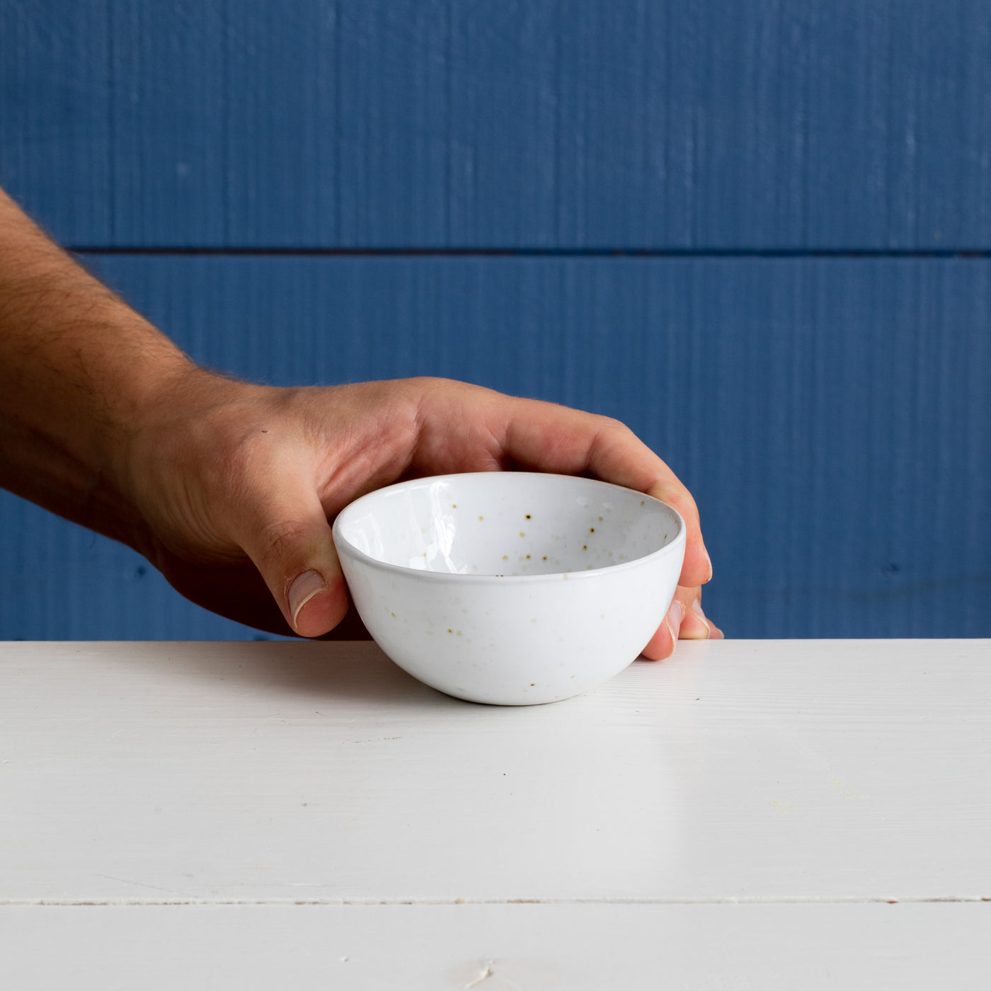 Small bowl for dips and nuts in white with golden spots against a blue background
