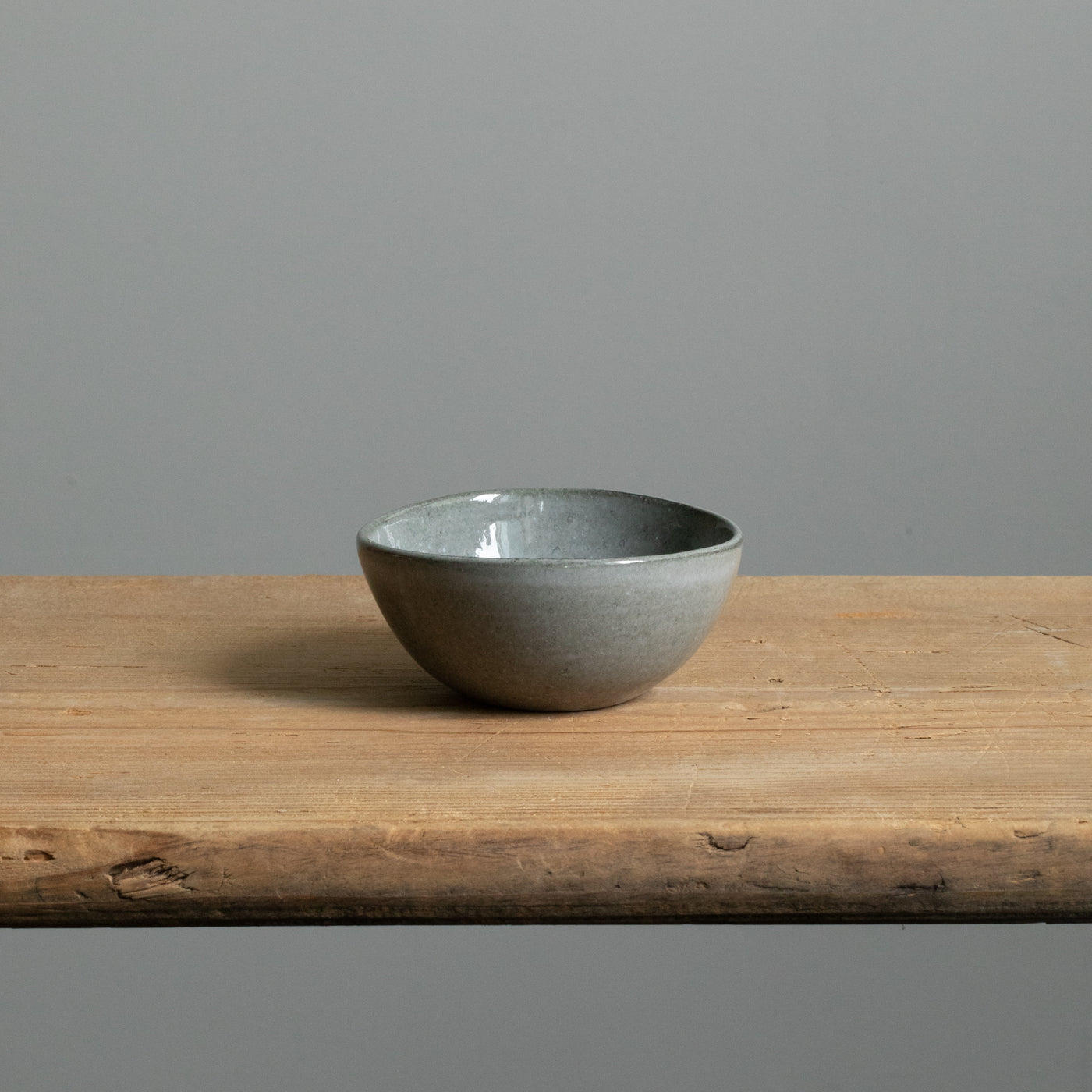Small bowl in dark gray glossy glaze perfect for antipasti standing alone on a wooden table