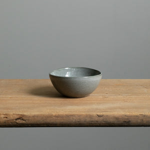 Small bowl in dark gray glossy glaze perfect for antipasti standing alone on a wooden table