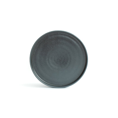 Small matt black plate with angled rim, positioned and cropped