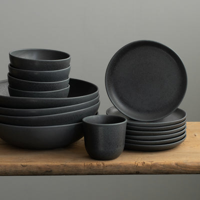 Matt black crockery set with pasta plates, large bowls, small and large plates stacked in stoneware