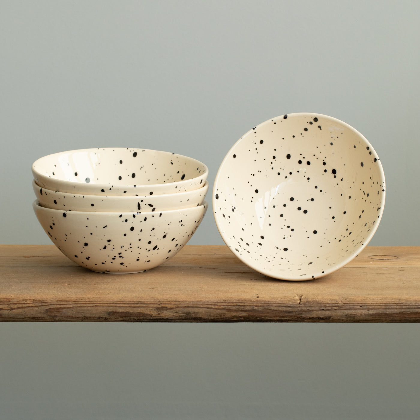 Three muesli bowls stacked on top of each other in cream color with black dots and an upright bowl