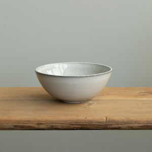 A light gray breakfast bowl with a slightly open rim on a wooden table