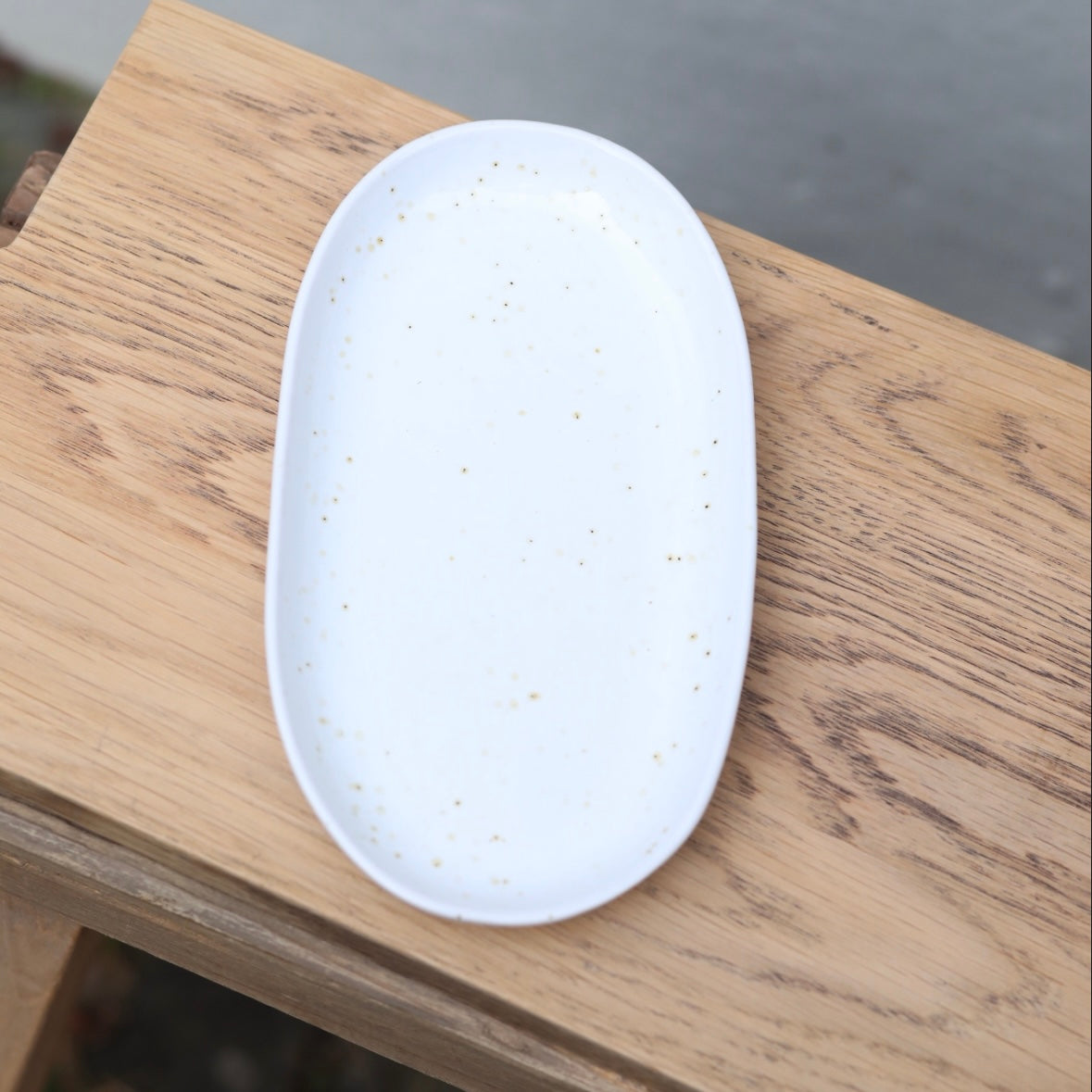 White 22cm oval plate photographed from above with fine brown sprinkles, perfect as a saucer