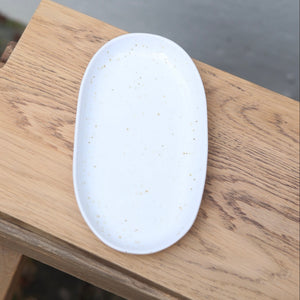 White 22cm oval plate photographed from above with fine brown sprinkles, perfect as a saucer