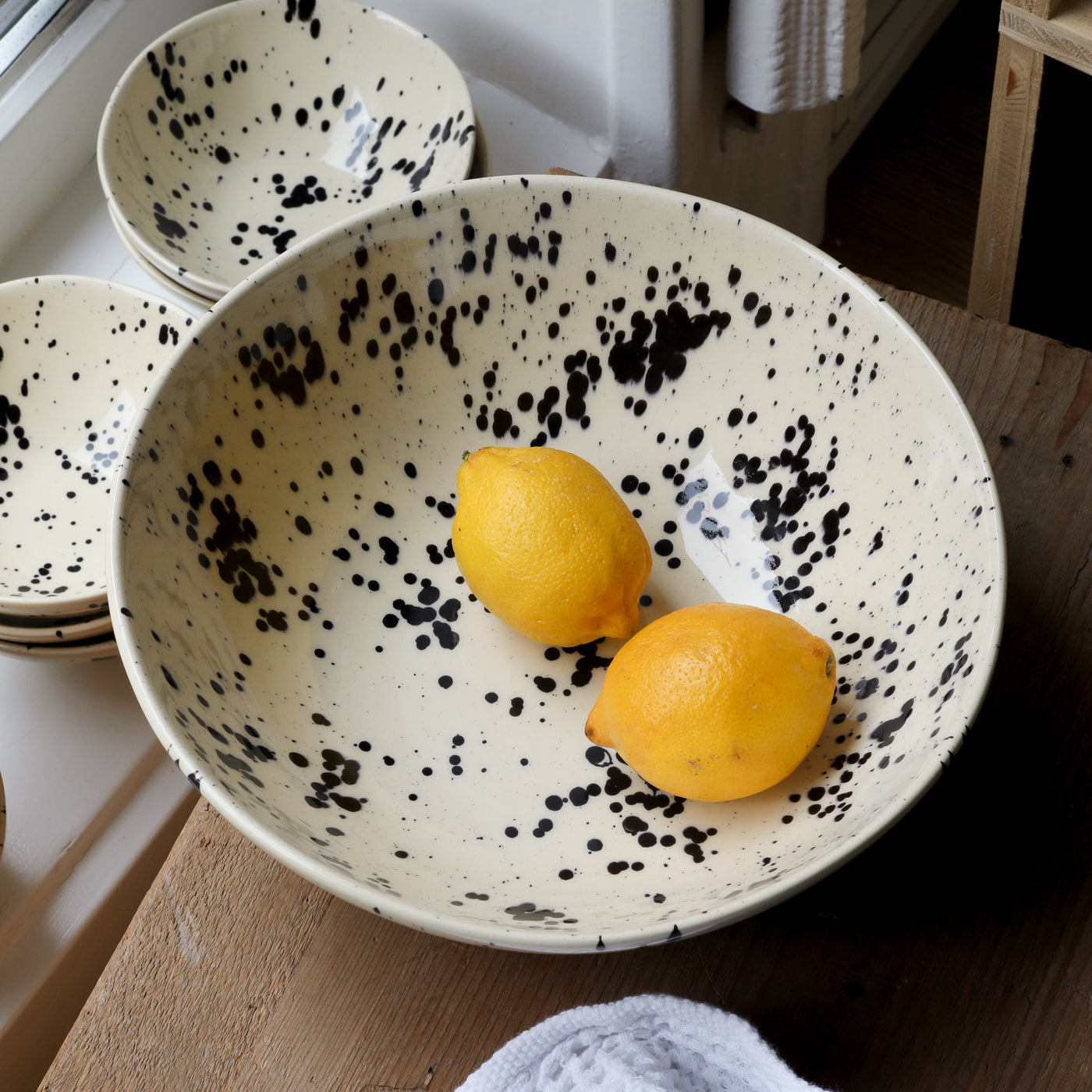 Two lemons lie in the black-dotted beige salad bowl