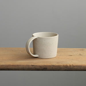 Tea cup with handle in beige on a wooden table