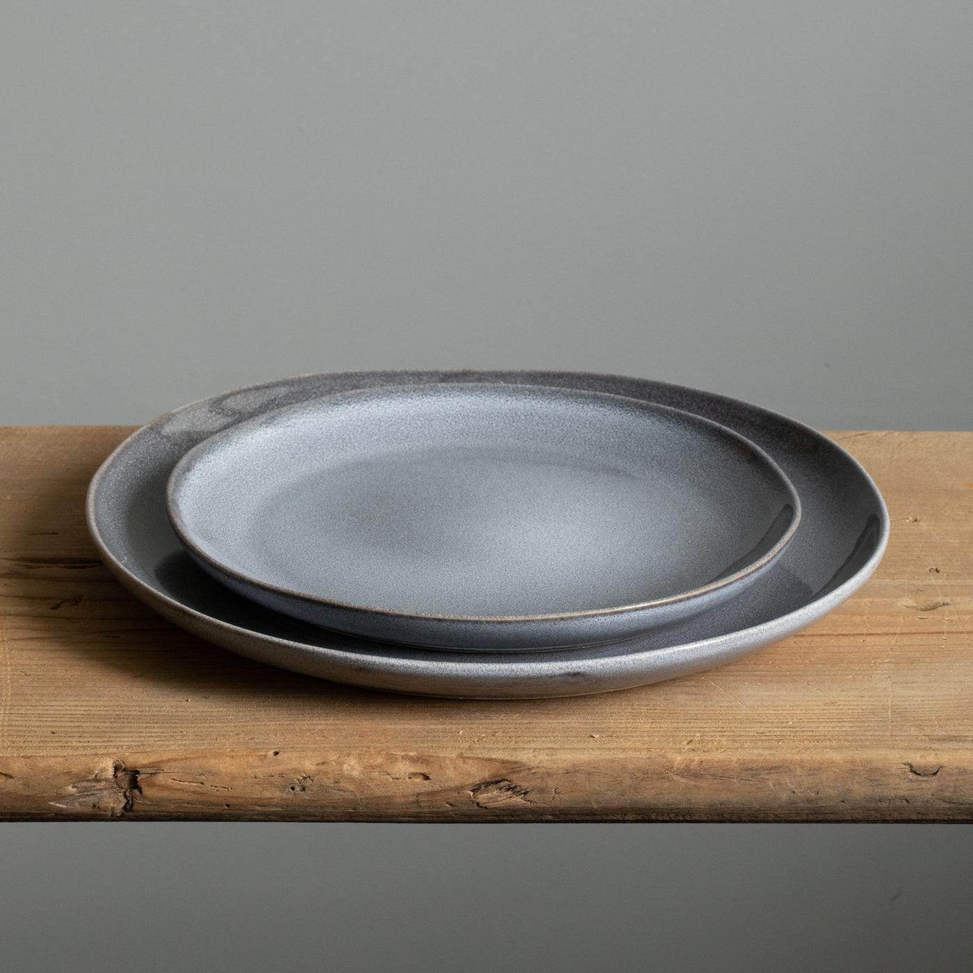 A large organic plate underneath a small blue starter plate made of robust stoneware