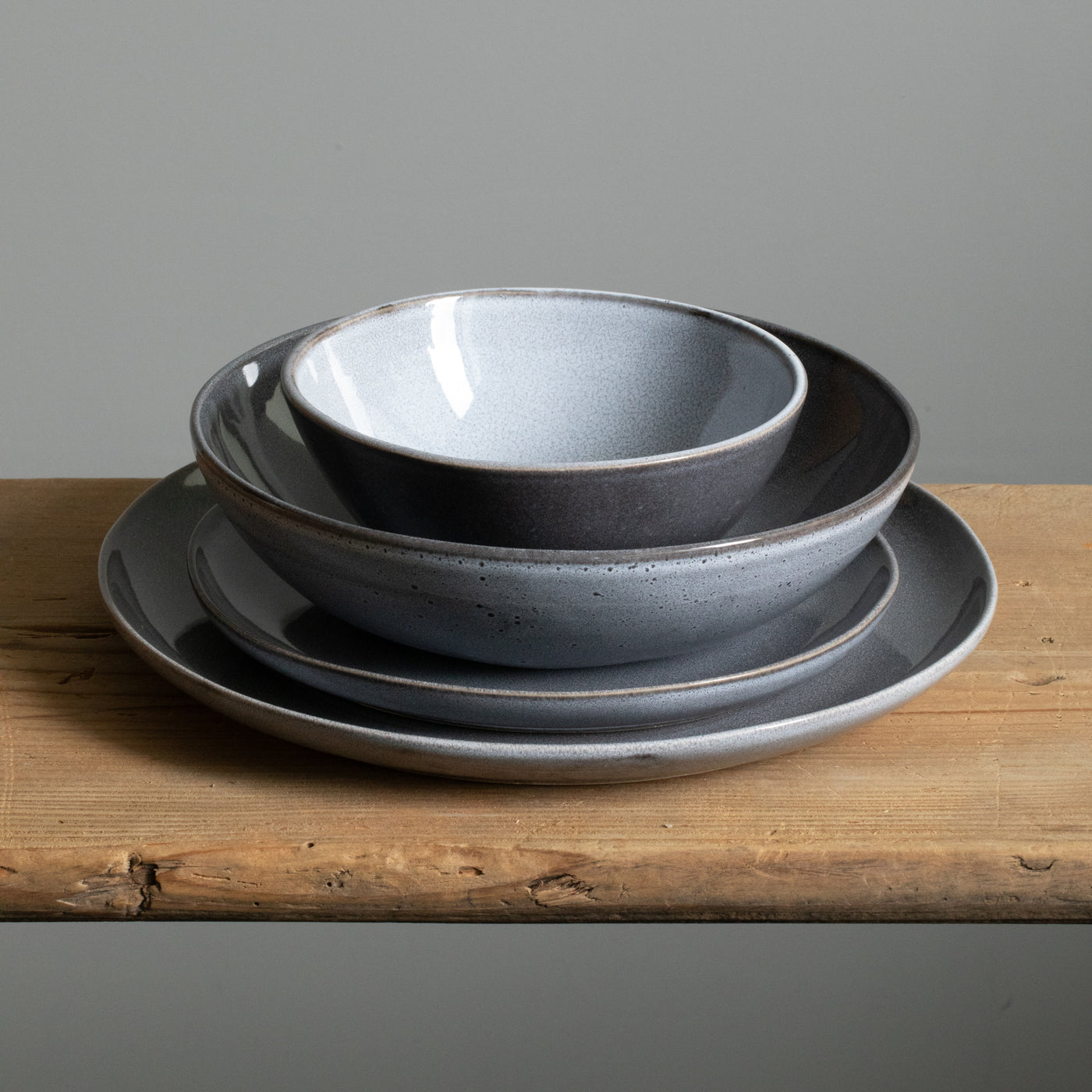 Complete stoneware tableware set stacked on top of each other. Large plate, small plate, pasta plate and a cereal bowl in blue