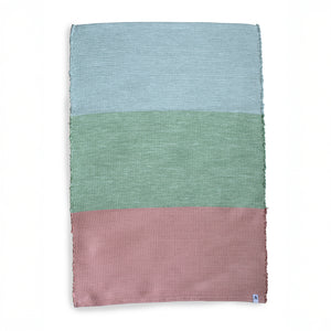 Clipping of a blue green pink color block carpet in front of a white background