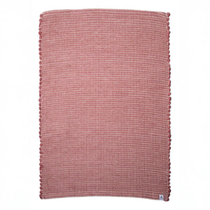 Small jute-striped rug in red made from wool remnants hand-woven in Portugal against a white background