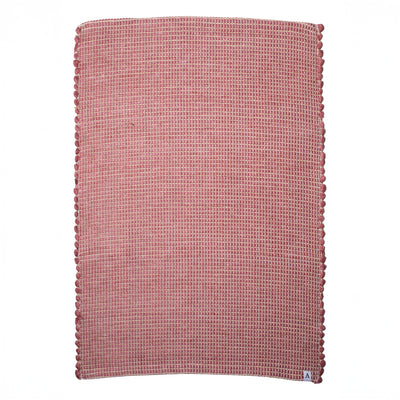 Small jute-striped rug in red made from wool remnants hand-woven in Portugal against a white background