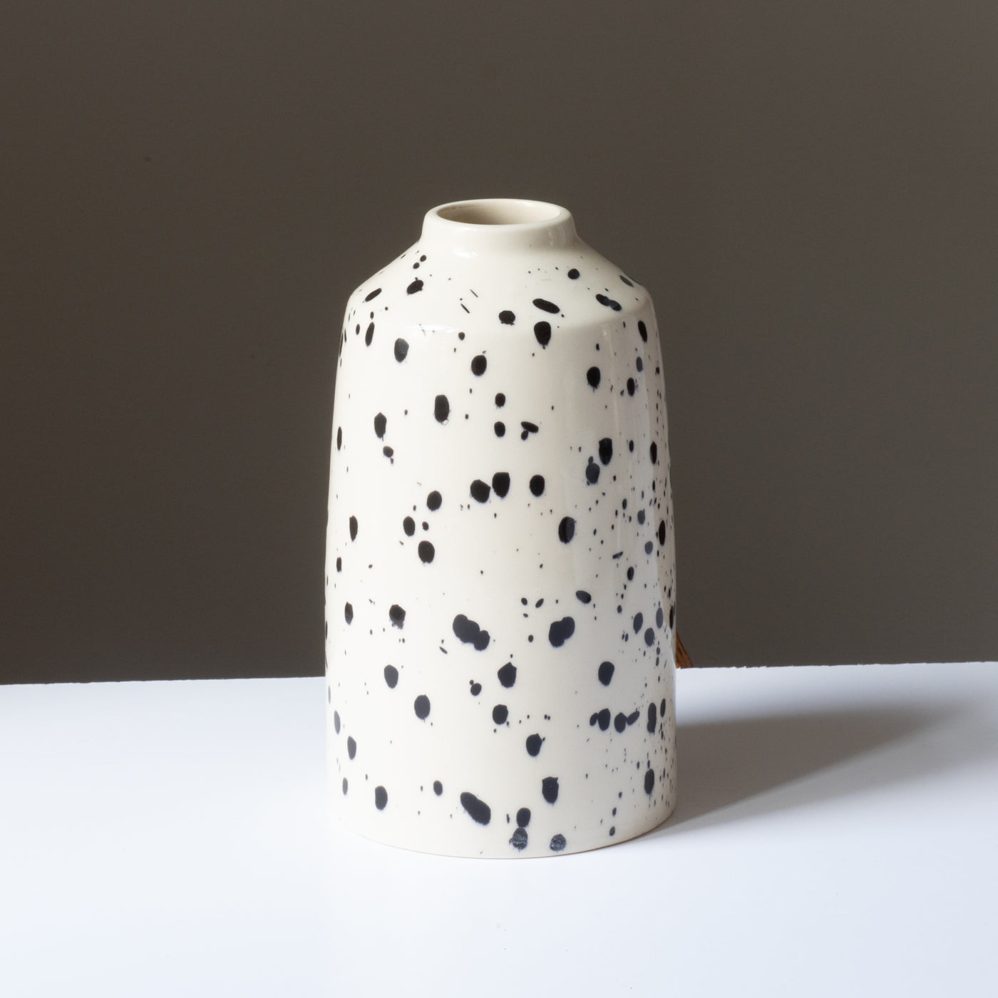 Cream-colored flower vase with black splashes of color and small opening