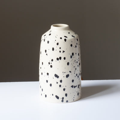 Cream-colored flower vase with black splashes of color and small opening