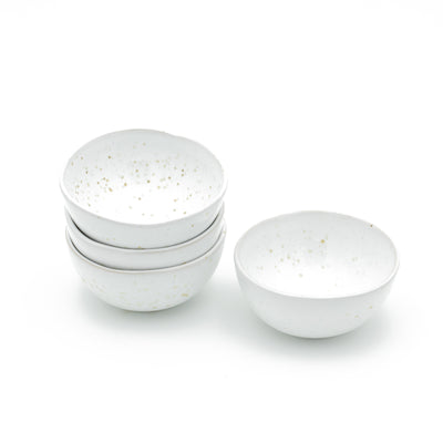 Three white bowls stacked on top of each other with yellow spots next to them against a white background